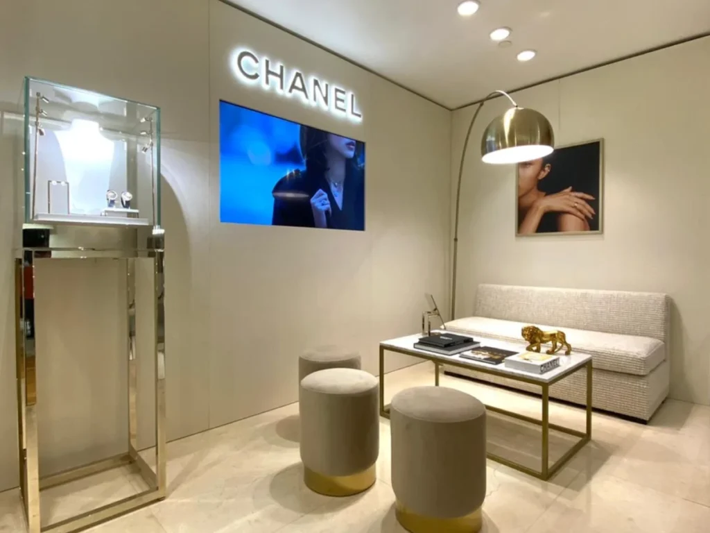 Zona de estar de Chanel en Lisboa con paneles de acabado textil, banco y taburetes