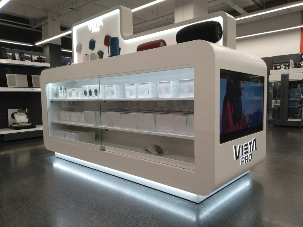 Expositor isla fabricado a medida para Vieta Pro, con vitrina iluminada y pantalla integrada, en una tienda de tecnología