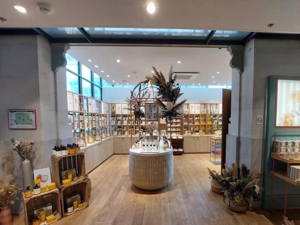 Expositor central con base de mimbre y estanterías de madera en la tienda de perfumería
