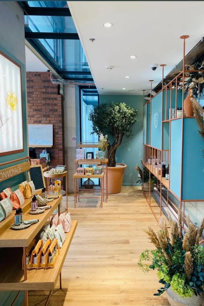 Zona de la tienda Panier des Sens en París con pared azul, estantería de madera y árbol decorativo